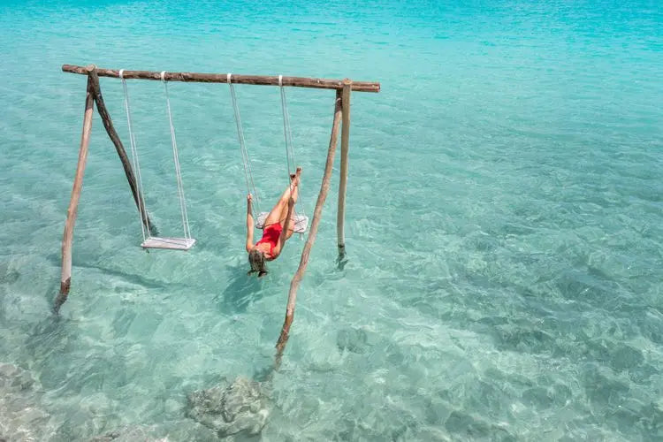 Swings standing in shallow turquoise water at Isla Columpios near Chuburná